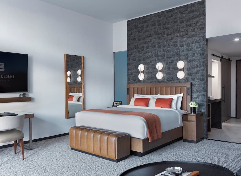 Black Desert Resort guest room with warm orange accents, woven mirrors, and modern desert-inspired design