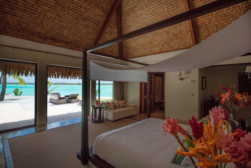 St. Regis Bora Bora villa interior with a thatched roof, canopy bed, and lagoon view