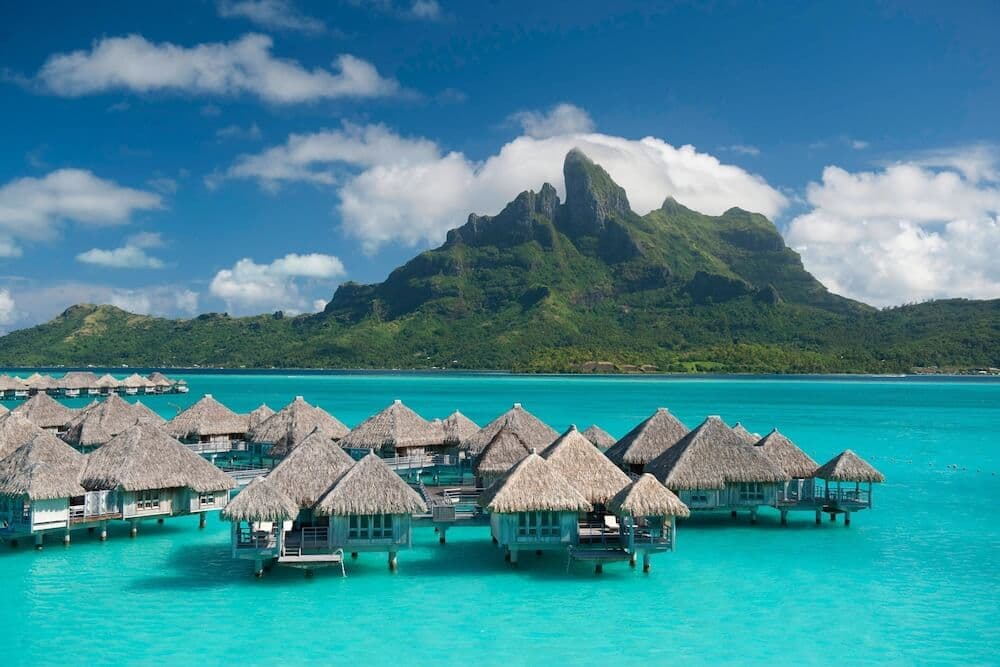 Overwater bungalows on the Bora Bora lagoon with Mount Otemanu rising behind them