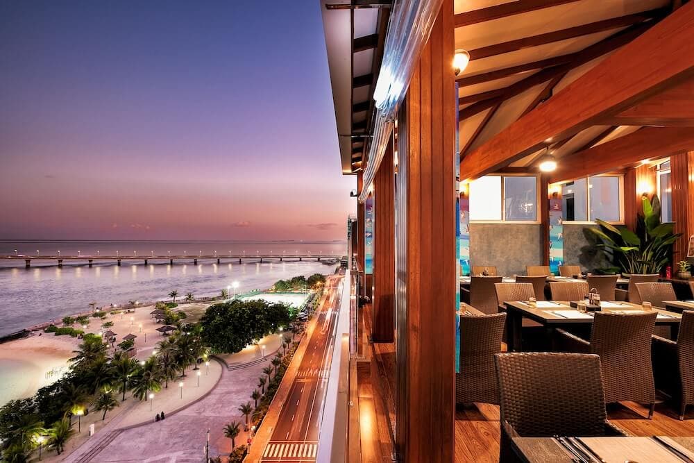 Rooftop terrace at Summer Beach Maldives at dusk overlooking Malé's beach and harbor